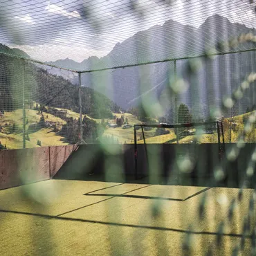 End of Season Herbsturlaub Onlinebuchungsangebot Fußballfeld im Freien mit Netz, umgeben von Bergen und grünen Hügeln